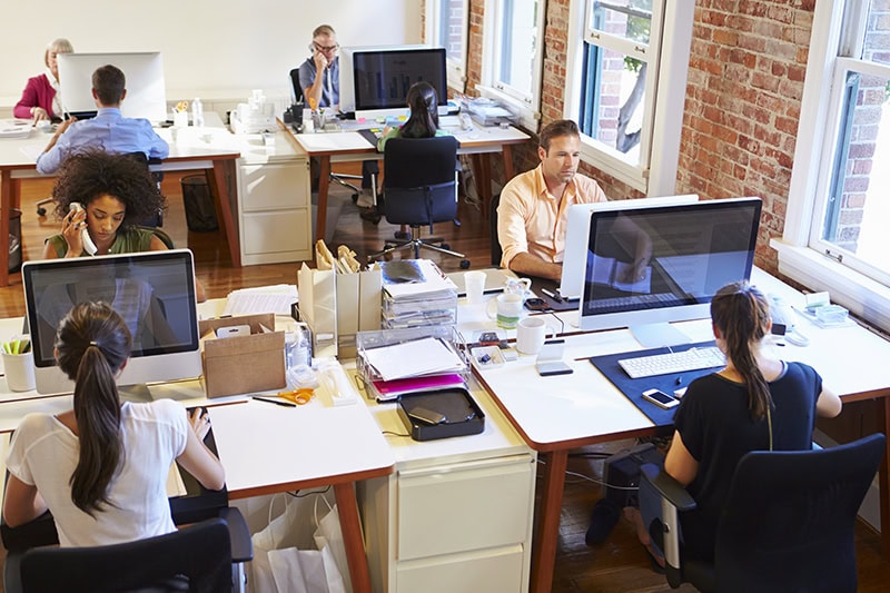 Wide Angle View Of Busy Design Office With Workers At Desks.