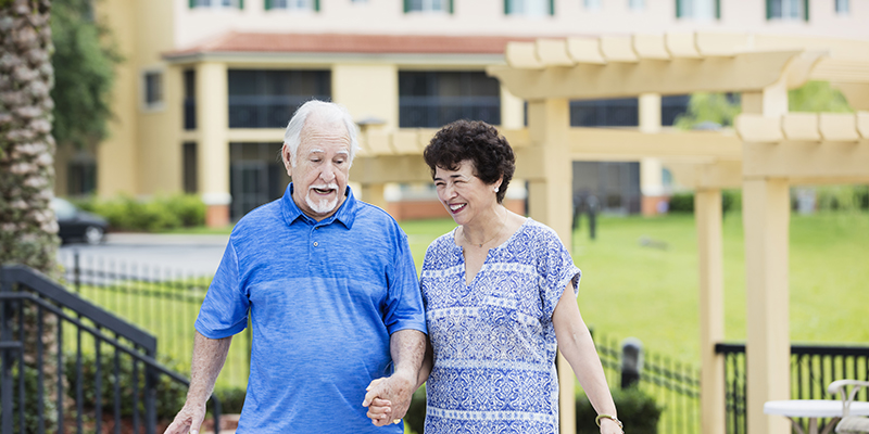 Senior Hispanic couple holding hands, talking, smiling